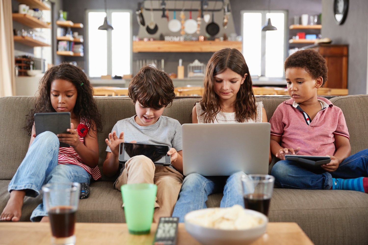 group-of-children-sitting-on-sofa-using-digital-P2SQMNK
